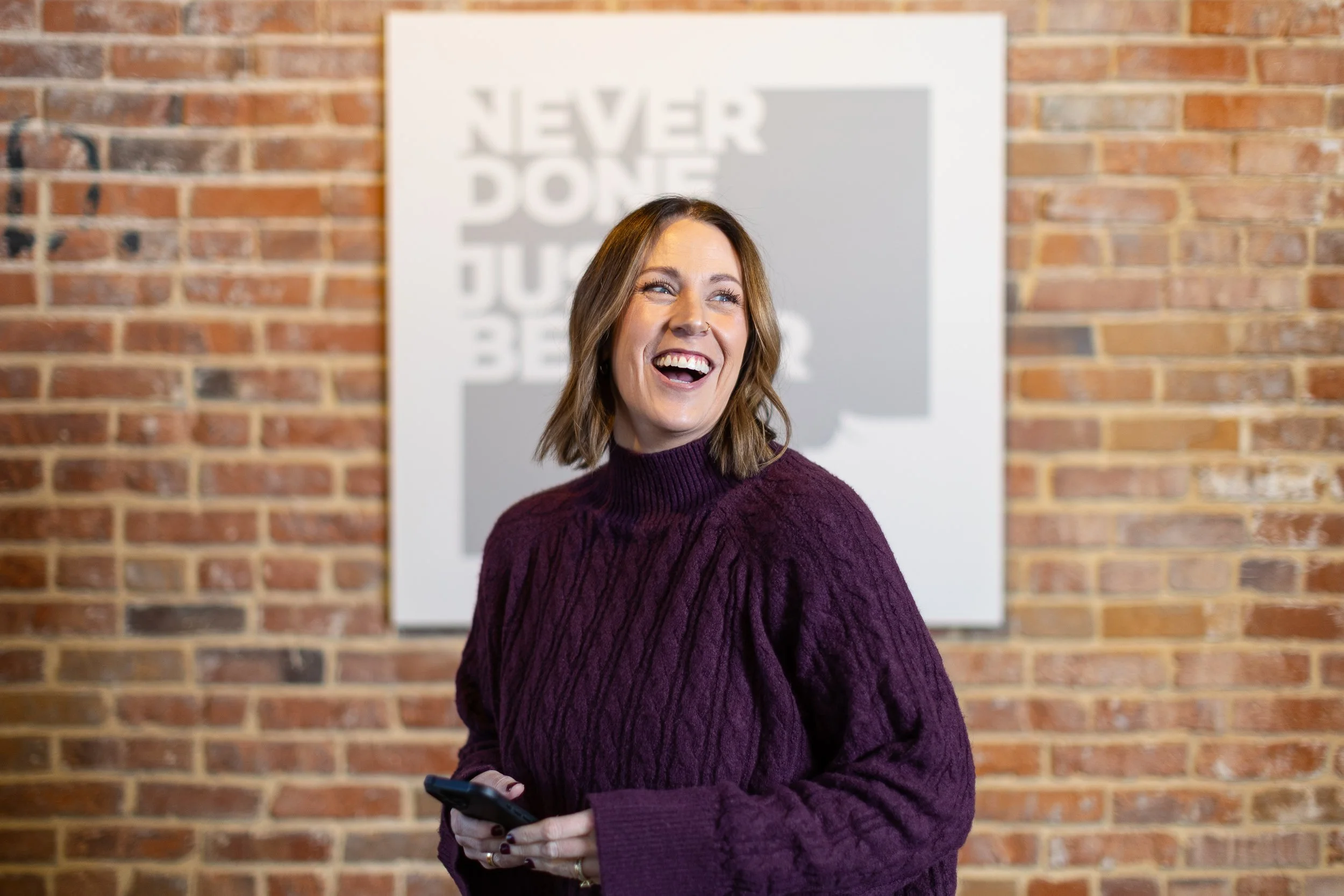 Chief operating officer for a marketing agency laughing while holding her phone during a branding photoshoot in Boise.