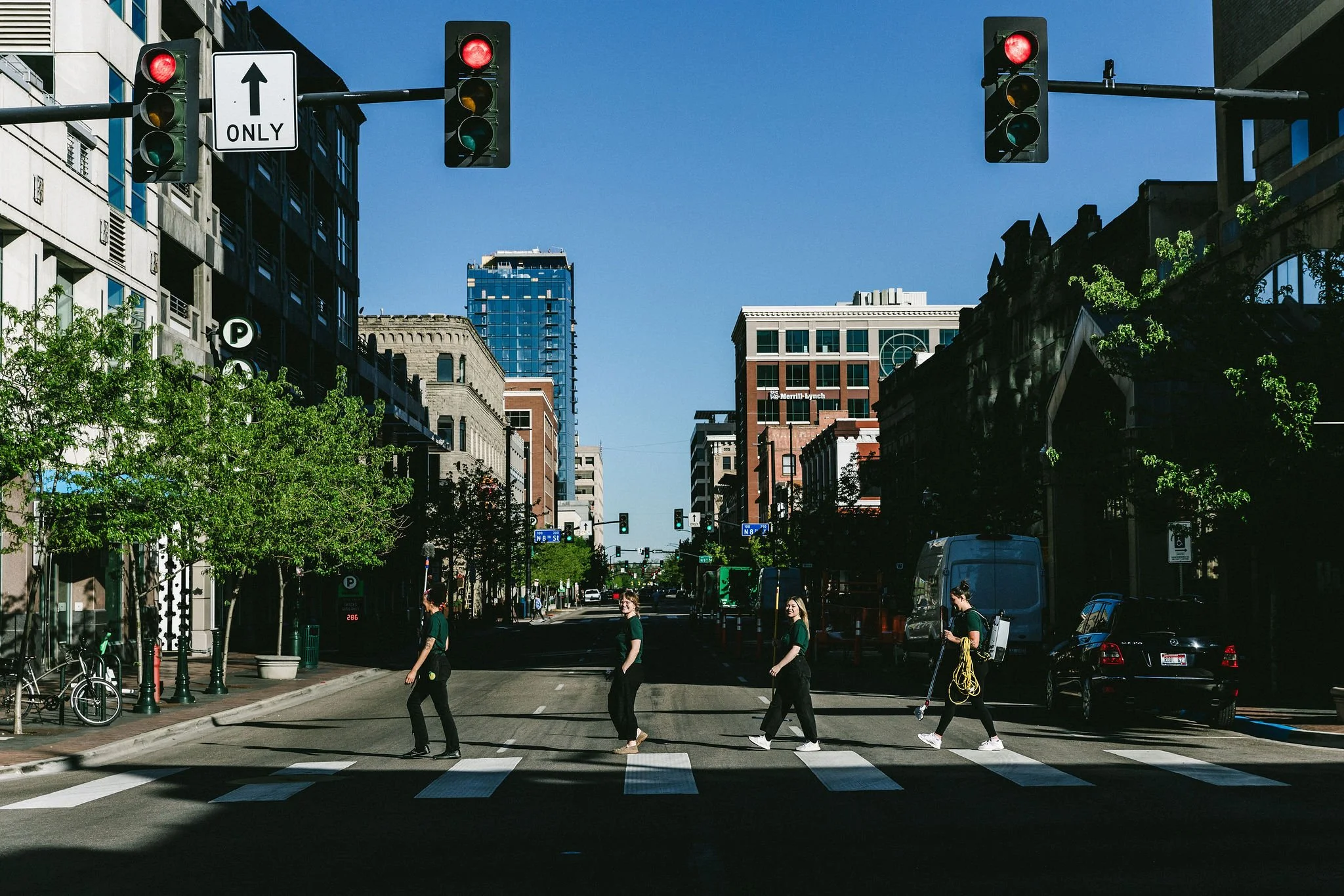 A pedestrian crosswalk in downtown Boise with four people walking across it during a branding photoshoot. Traffic lights are visible overhead, with most showing red light.