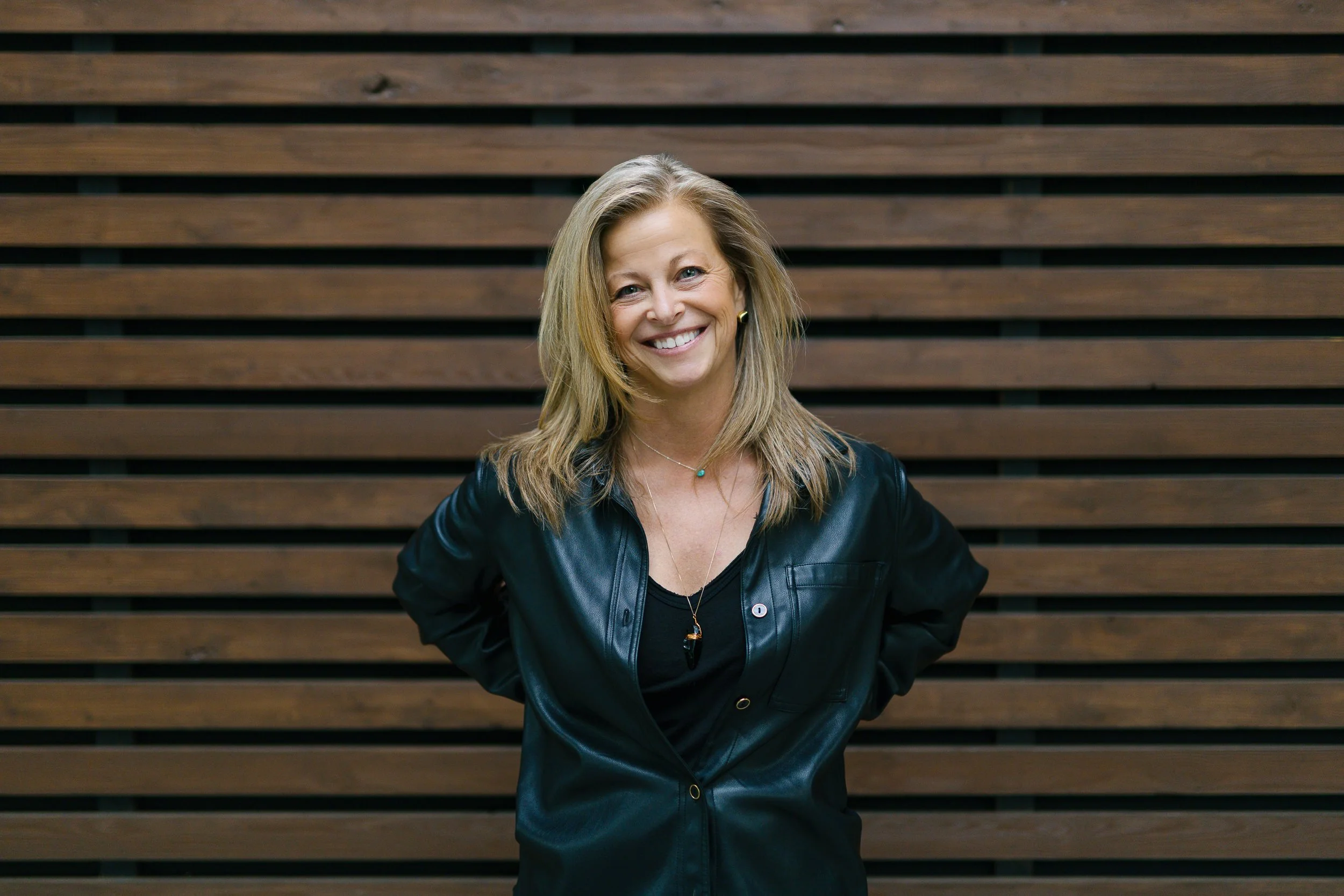 Woman keynote speaker smiling in front of a wooden wall during a branding photography session in Downtown Boise.