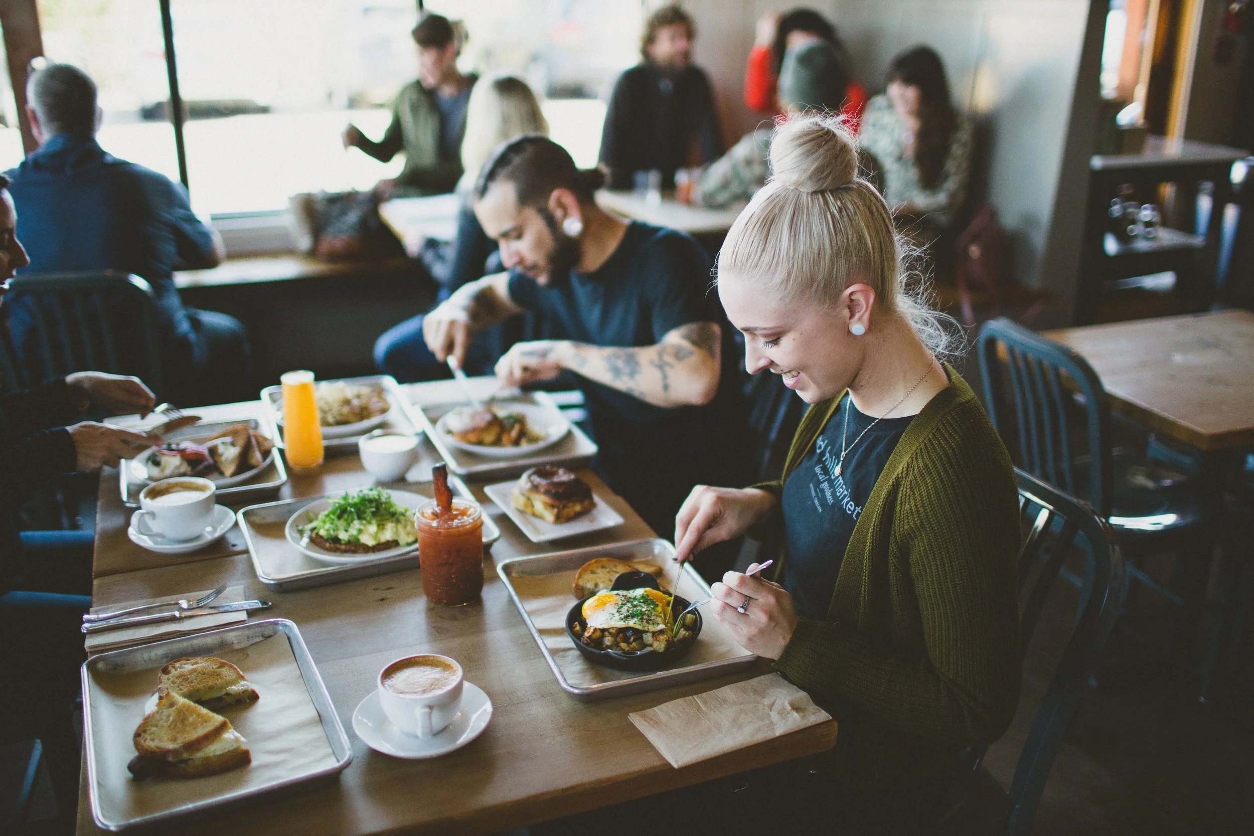 A group of people having breakfast in a cozy restaurant, with toast, coffee, and various breakfast dishes on the table during a branding photoshoot in Dundee, Oregon.