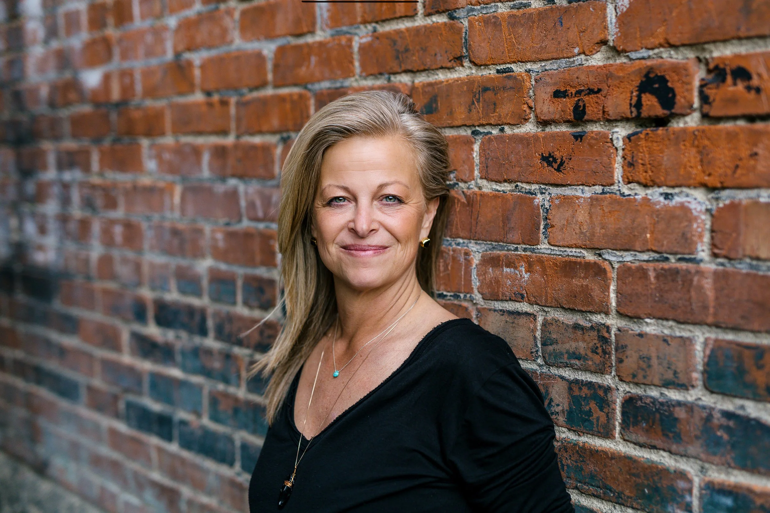 Woman business owner smiling softly and authentically looking at the camera during a branding photoshoot in downtown Boise.