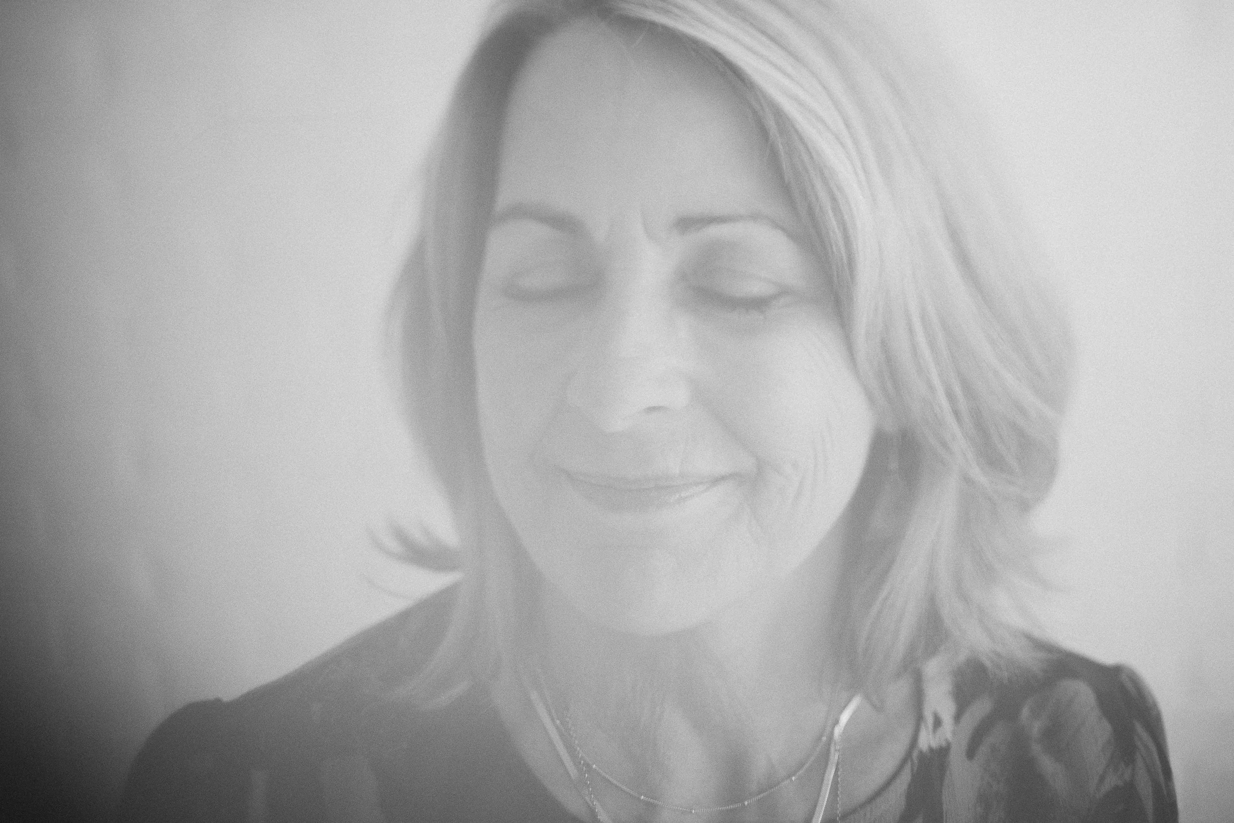 Woman business owner smiling slightly with her eyes closed during a personal branding photography session in a studio in downtown Boise.