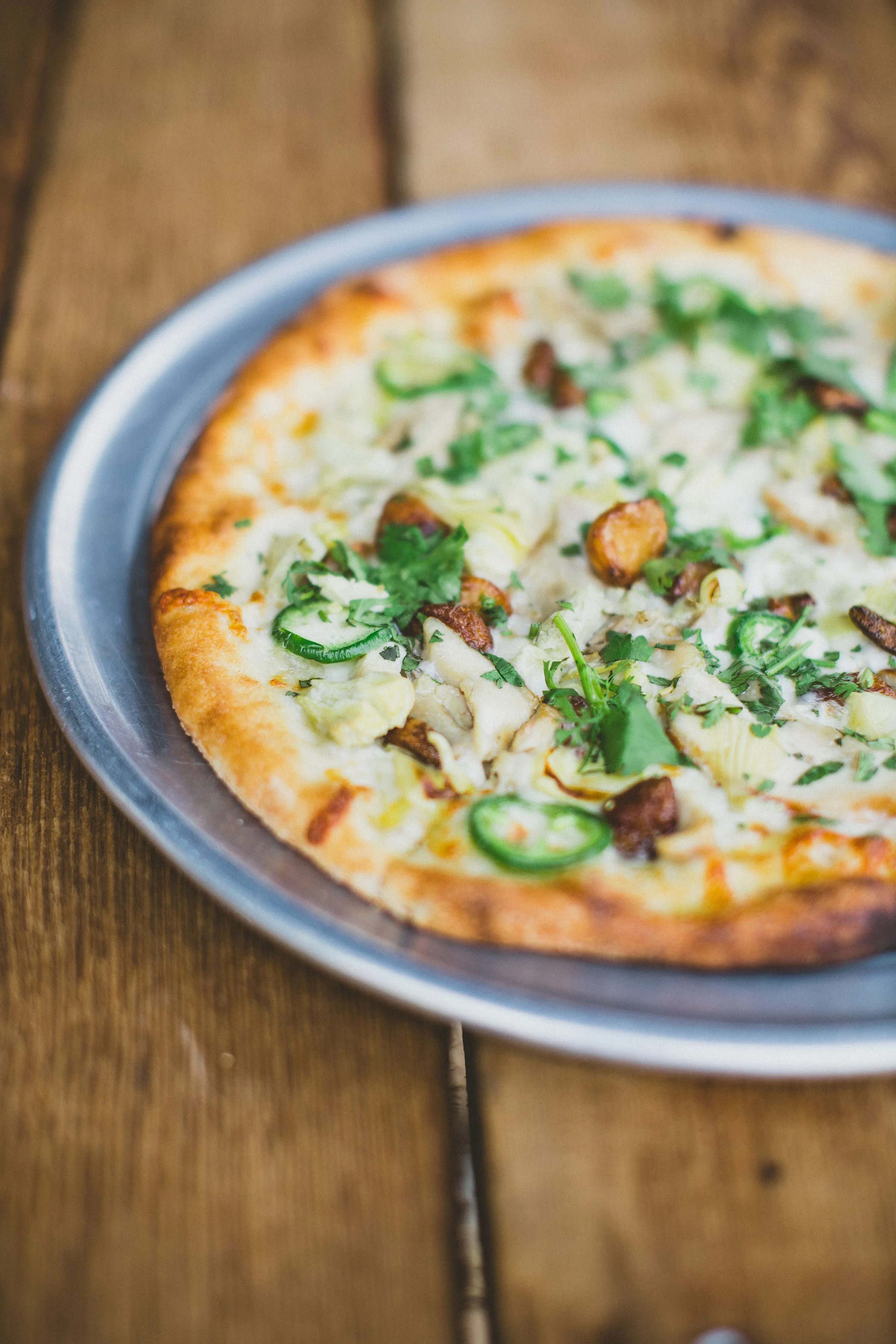 A pizza with green peppers, cilantro, and mushrooms on a metal tray during a branding photoshoot in Dundee, Oregon.