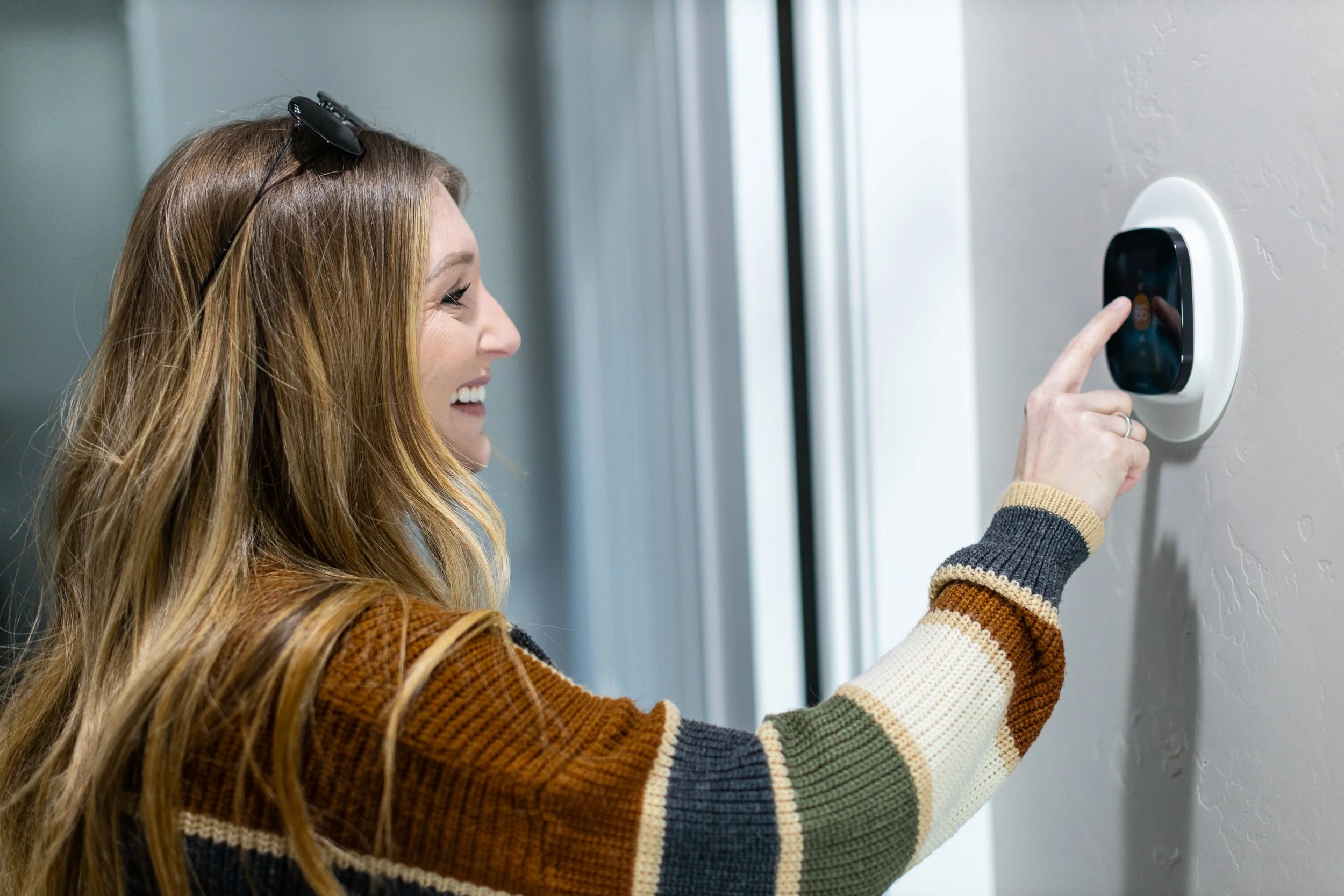 Smiling woman adjusts her thermostat during an hvac commercial photoshoot in Boise.