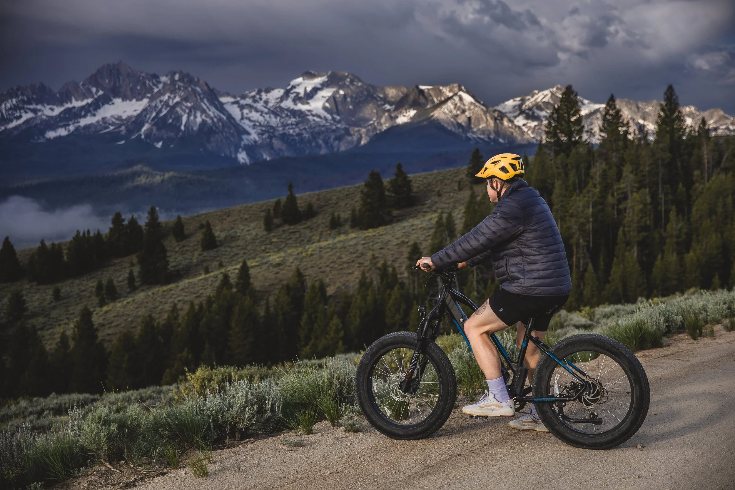 Man riding an e-bike on a gravel road at the base of the Sawtooth Mountains in Stanley Idaho during a branding photography session.