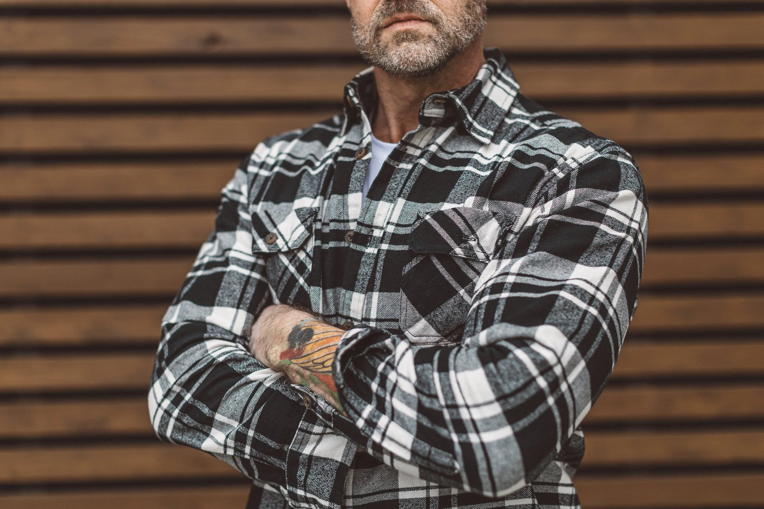 Authentic personal branding photography for a male entrepreneur with his arms crossed in front of a wooden wall in downtown Boise.