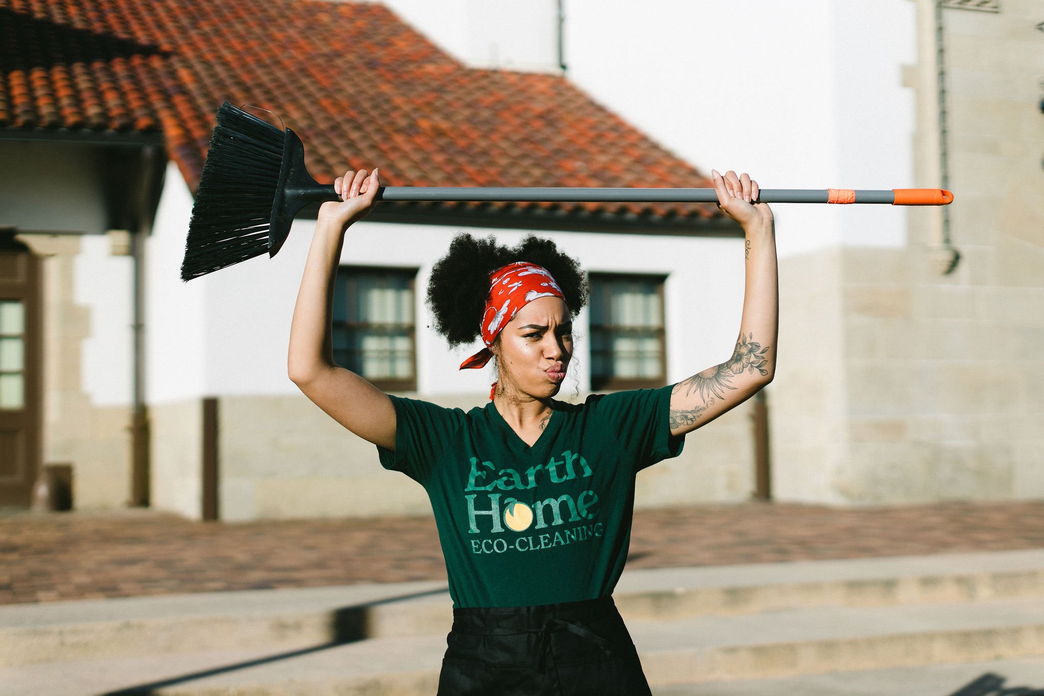 Creative lifestyle branding photo of a woman house cleaner holding a broom over her head during a lifestyle branding photoshoot at the boise train depot