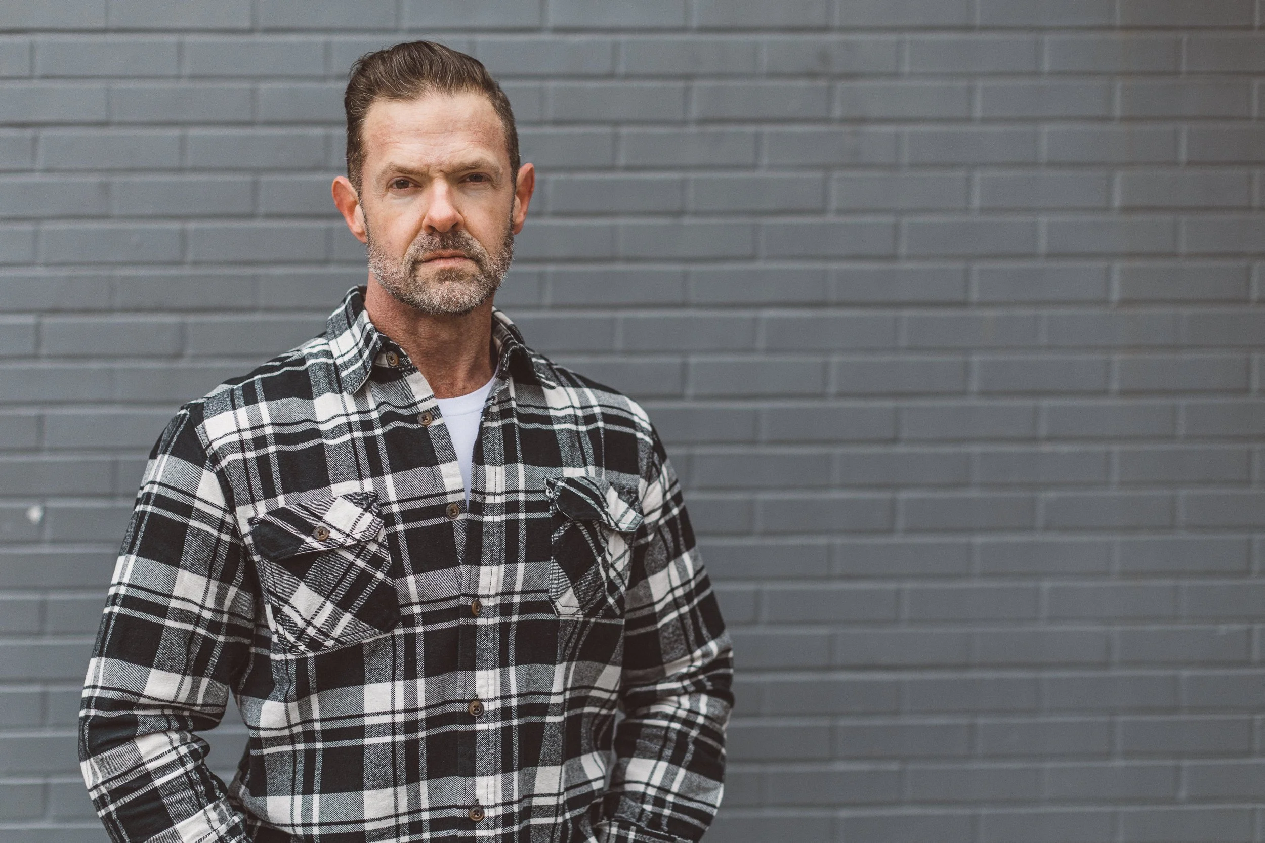 Personal branding photography for an entrepreneur in downtown Boise against a grey brick wall.