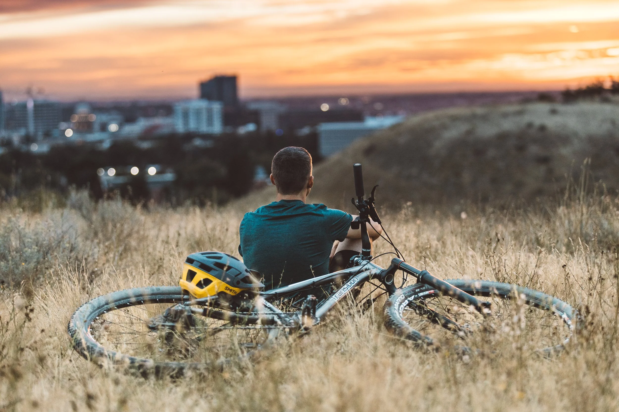 Personal branding photography in the Boise Foothills featuring an entrepreneur mountain biking at sunset with downtown in the background during a Boise branding photoshoot.