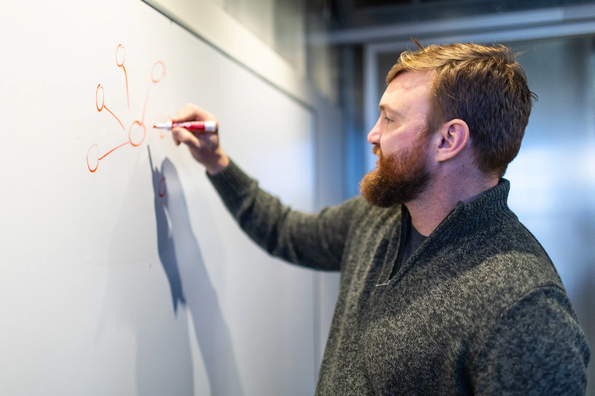 The digital director for a marketing agency in Boise writing on a white board during a meeting during a branding photoshoot.