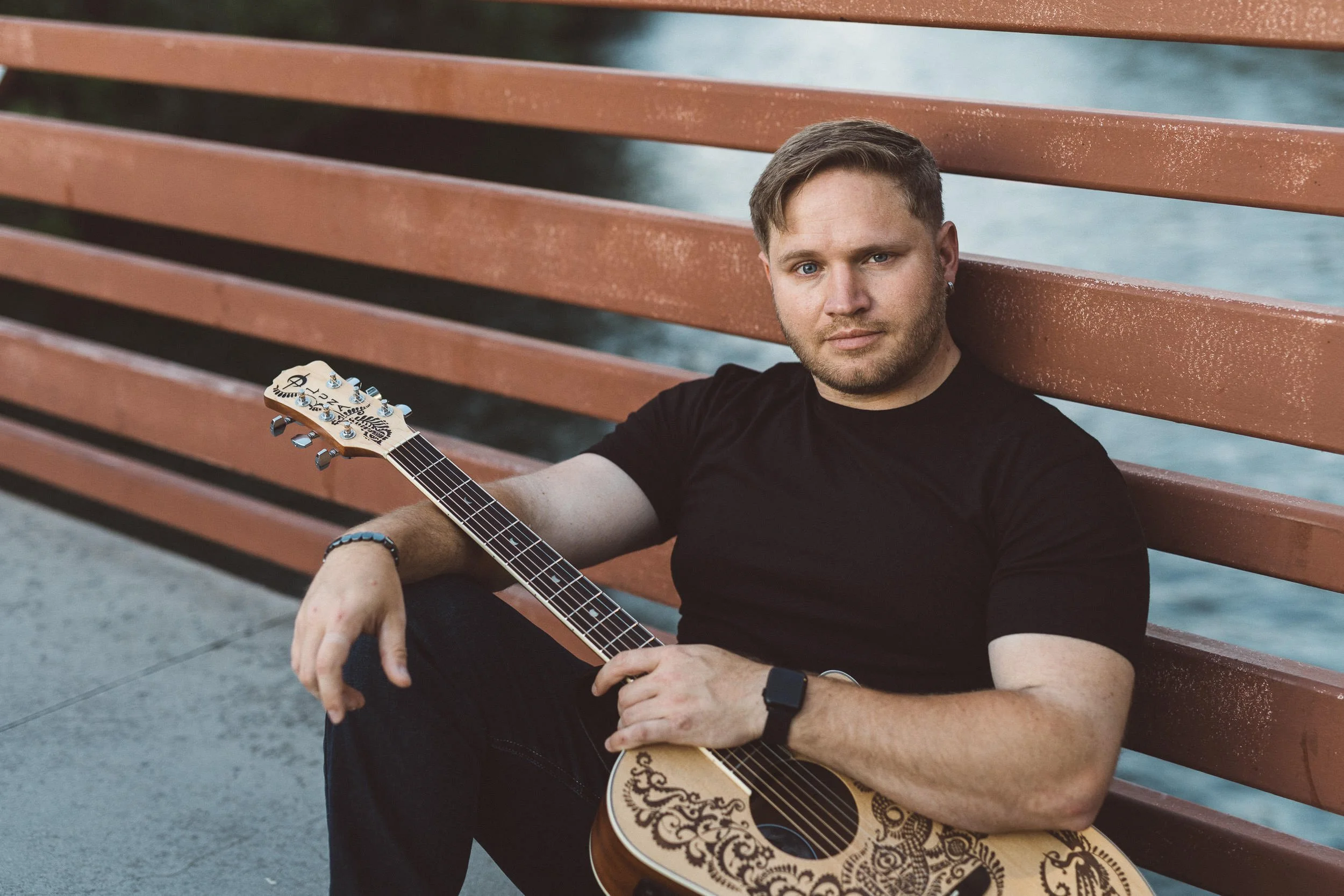 Musician Brandon Greenway looking at camera holding guitar during a branding photoshoot at sunset in Boise.