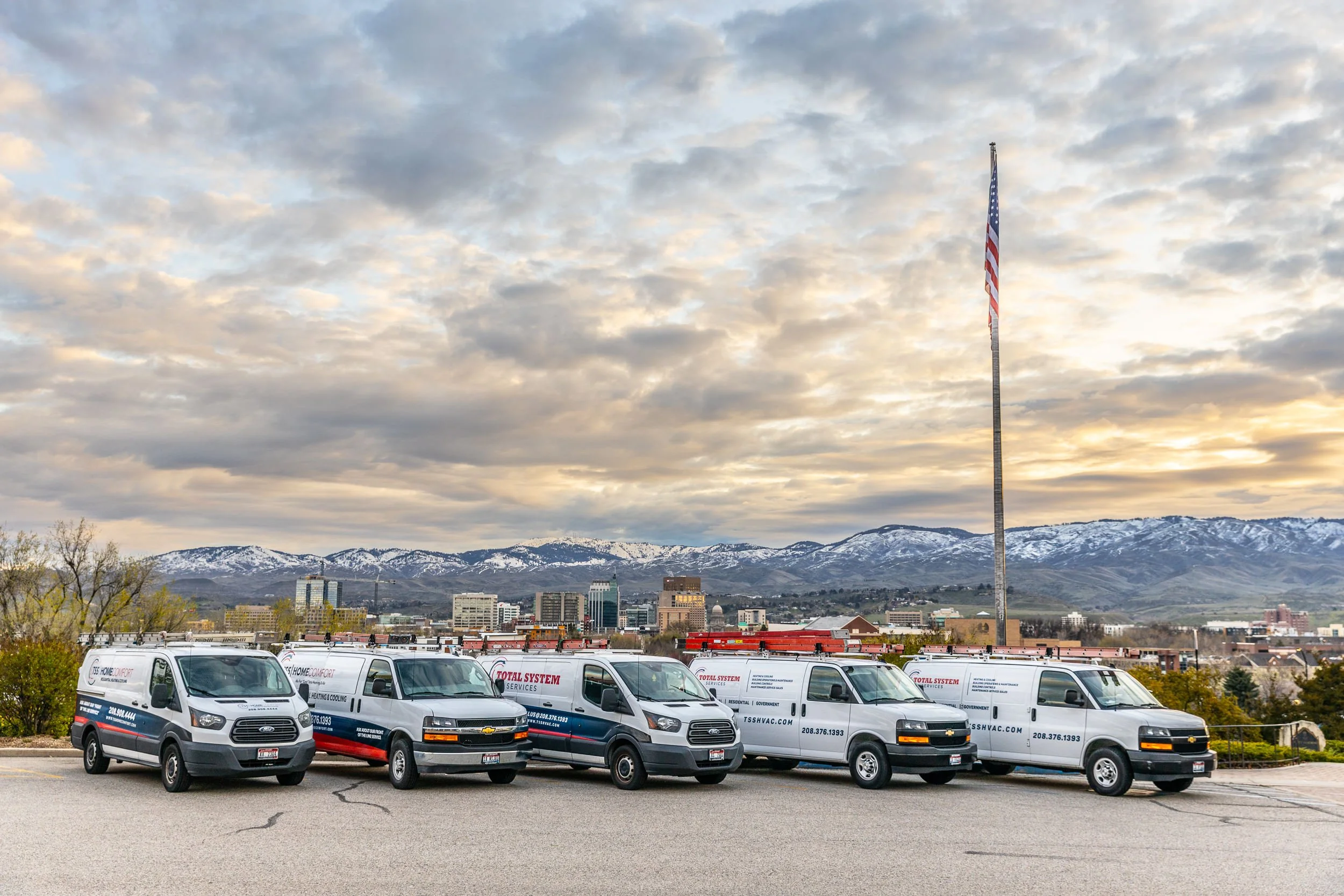 HVAC company fleet of vehicles at sunrise with downtown Boise and the foothills in the background during a commercial photoshoot.