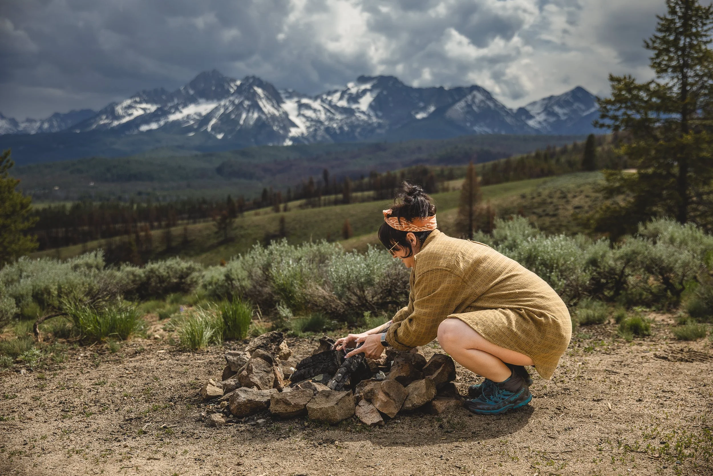 Branding photography session of a woman starting a campfire while camping on nip and tuck road in Stanley, Idaho at the base of the Sawtooth Mountains
