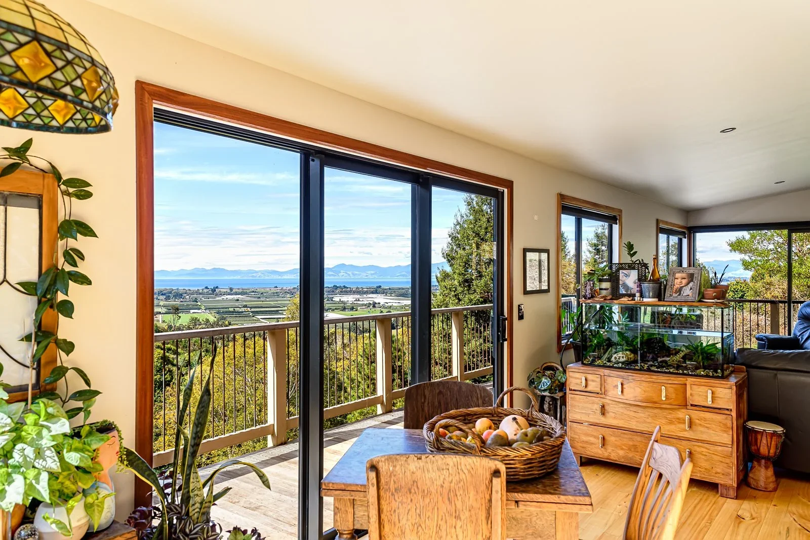 Living room with large sliding glass doors opening onto a balcony with scenic view of mountains and landscape.