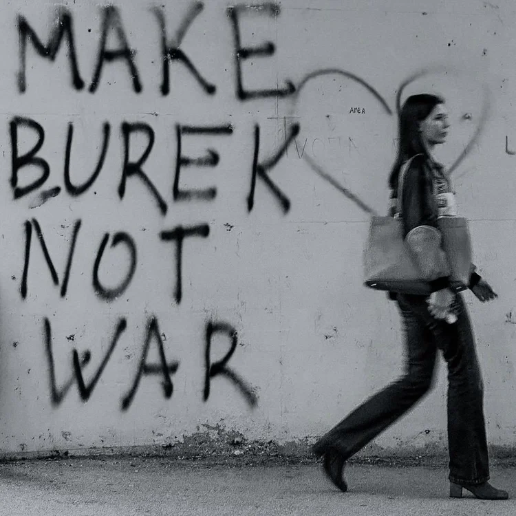 A woman passing graffiti that reads Make Burek Not War