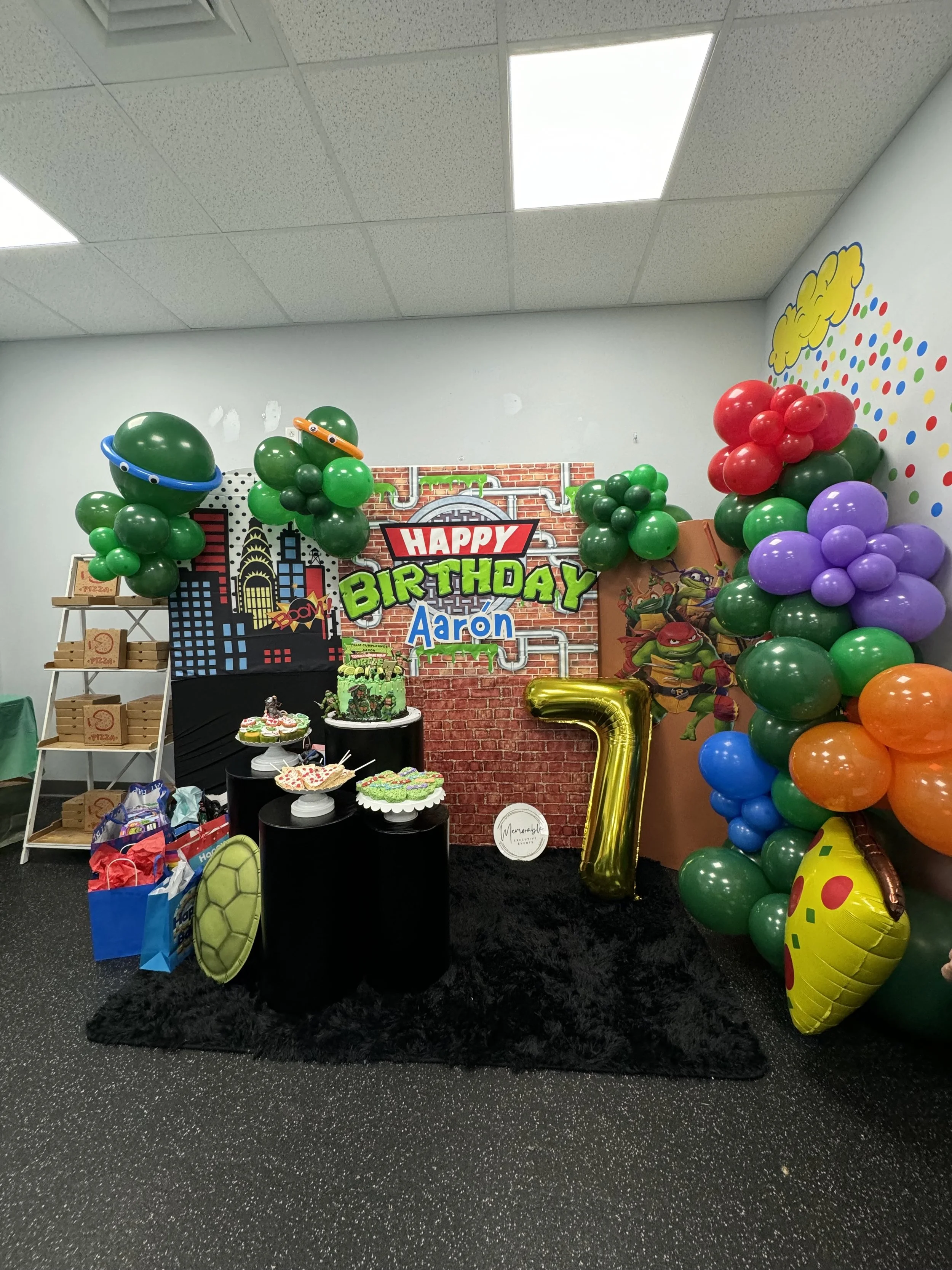 Colorful birthday party setup with balloons, cakes, and Teenage Mutant Ninja Turtles decorations.