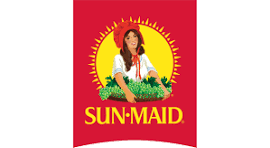 Illustration of a woman with brown hair in a red dress with white sleeves, standing behind a garden of leafy greens and vegetables, surrounded by a yellow sunburst on a red background. The text 'SUN-MAID' appears below.