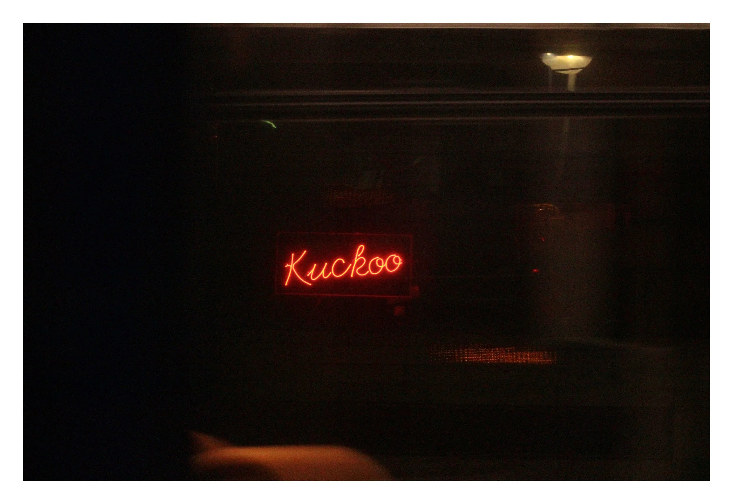 A dark image with a red neon sign that says 'Kuchoo' in the center.