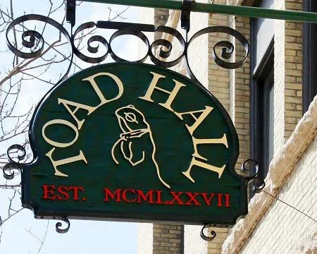 A green circular sign for a business named 'Road Hall' with a dog silhouette and the establishment year 2017 listed in Roman numerals.