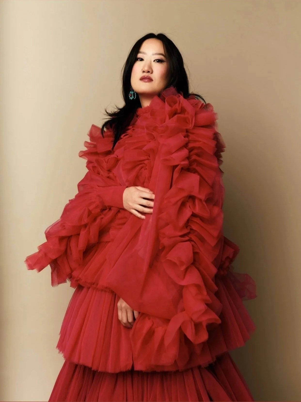A woman with long black hair wearing a red ruffled dress.