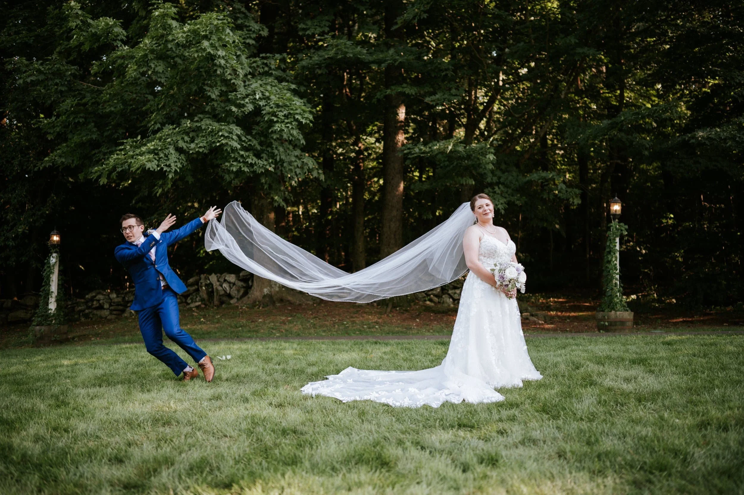 A bride standing for portraits while the groom tosses the vail and trying to run out of the frame