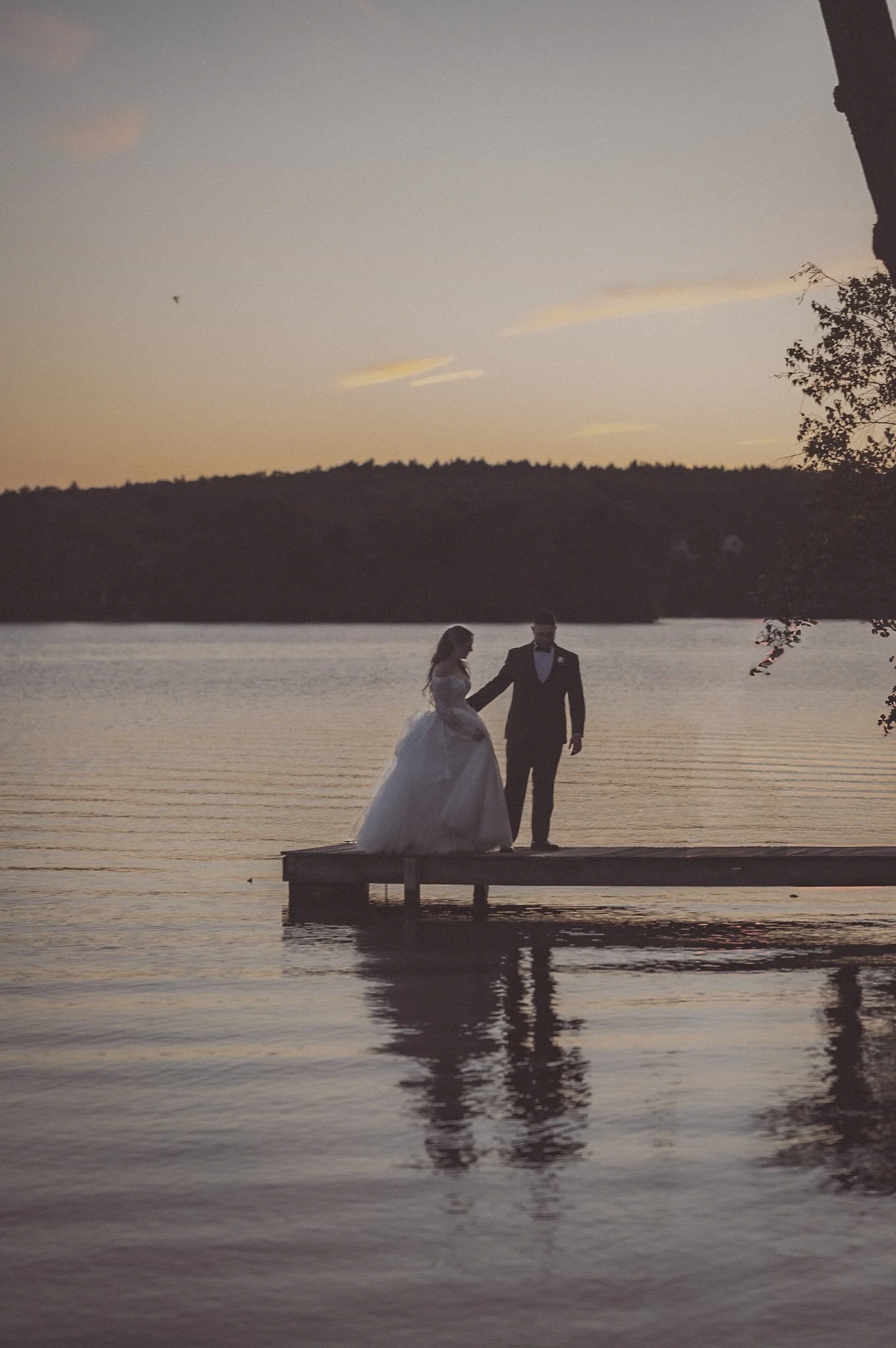 Image by Meg & Co. Studios of a couple on a dock at golden hour during their wedding day at Lake Pearl in MA