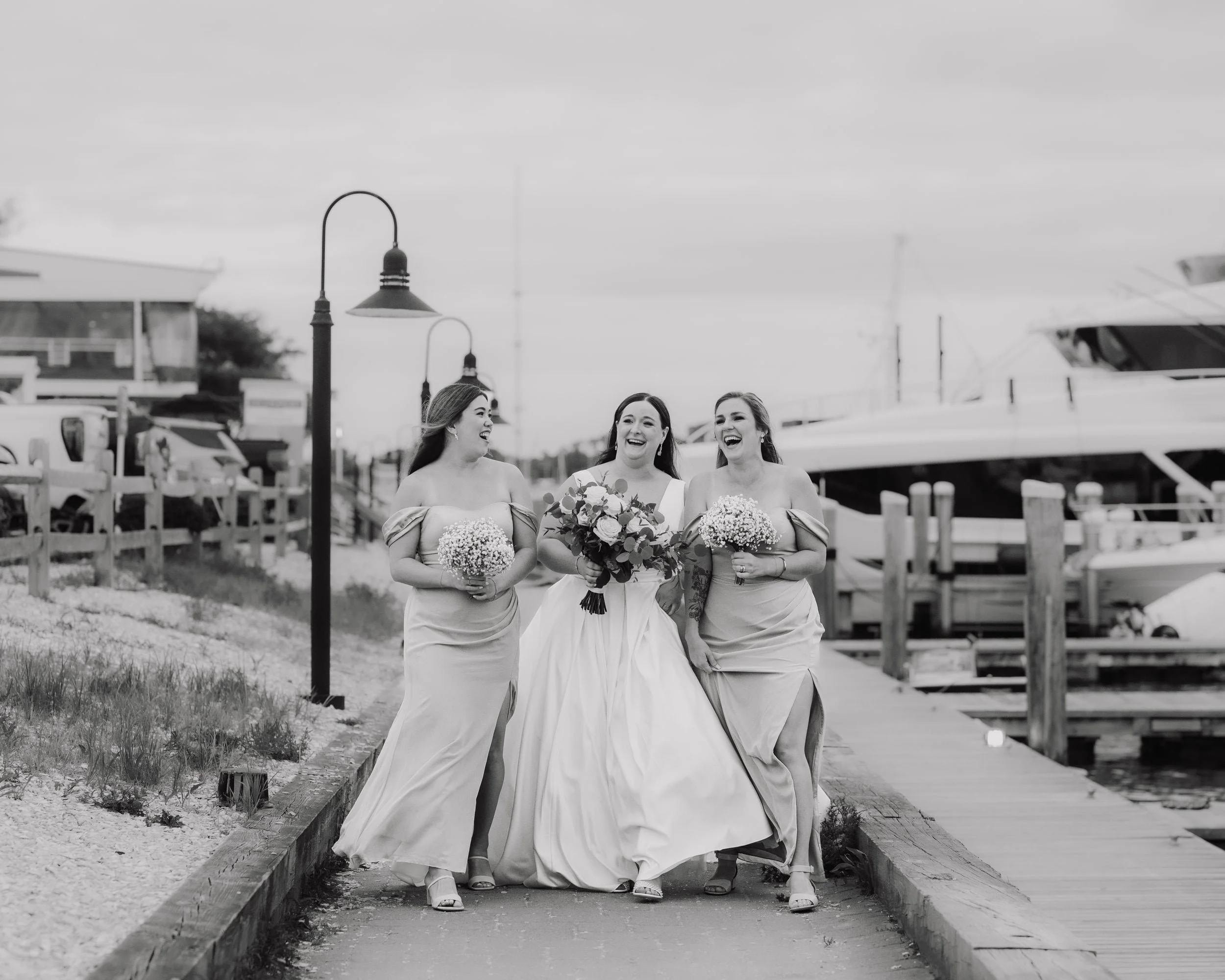 A Bride and her bridesmaids walking on a boardwalk in cape cod
