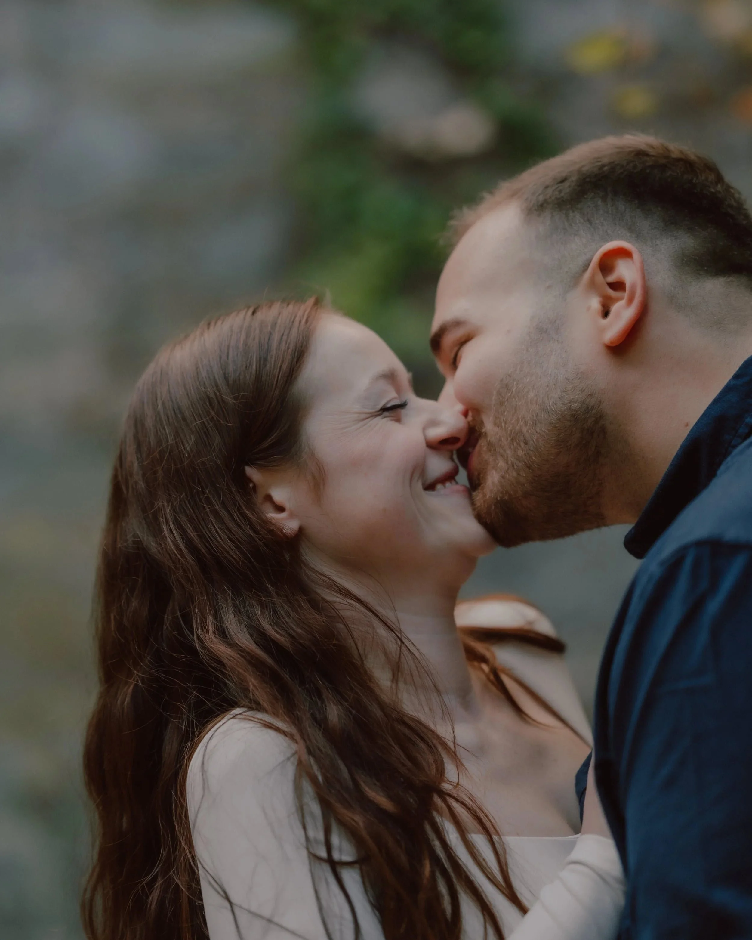 A couple playfully kissing during their engagement photography session in massachusetts