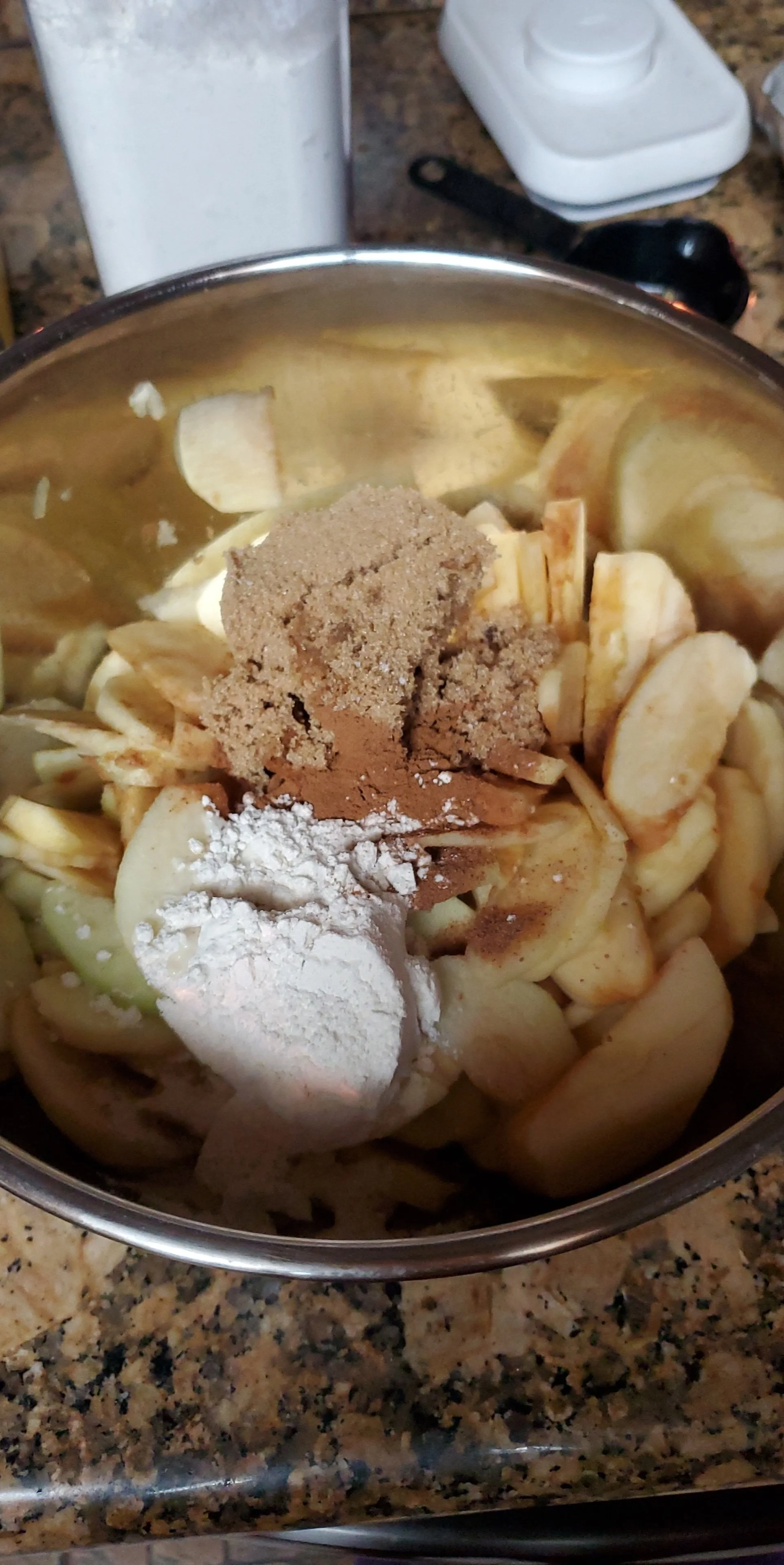 A bowl of sliced bananas topped with cinnamon, sugar, and flour, ready for cooking or baking.