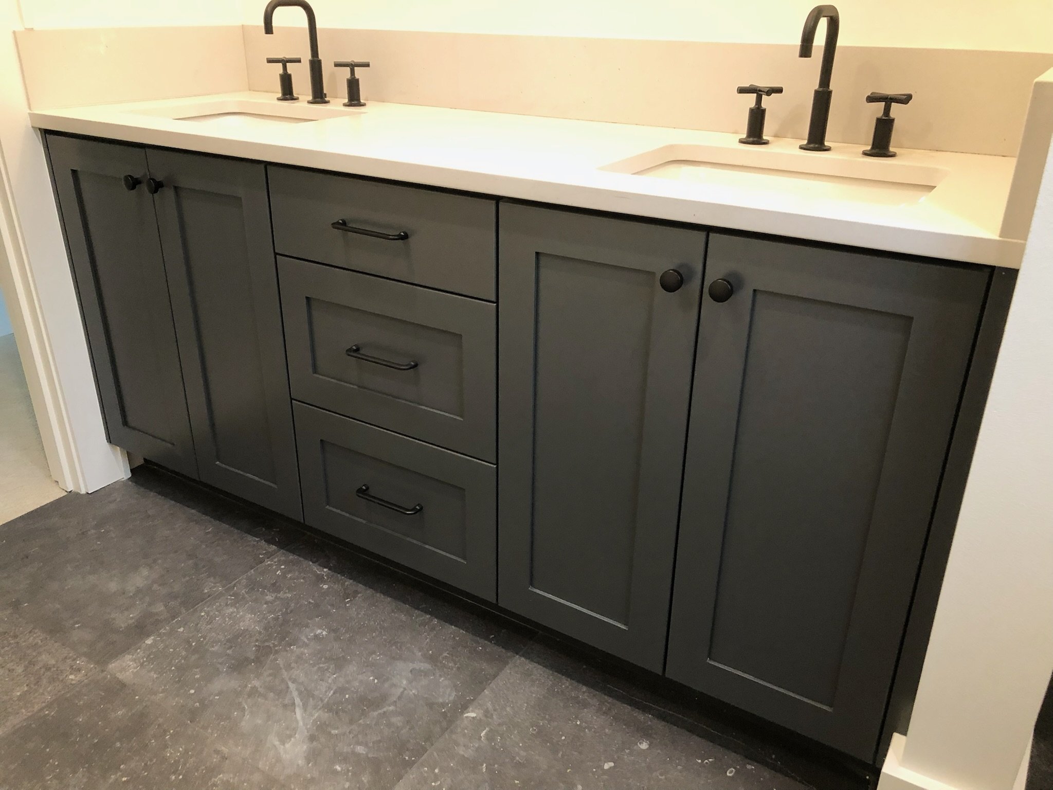 Dark gray bathroom vanity with two sinks, black fixtures, and a white countertop.