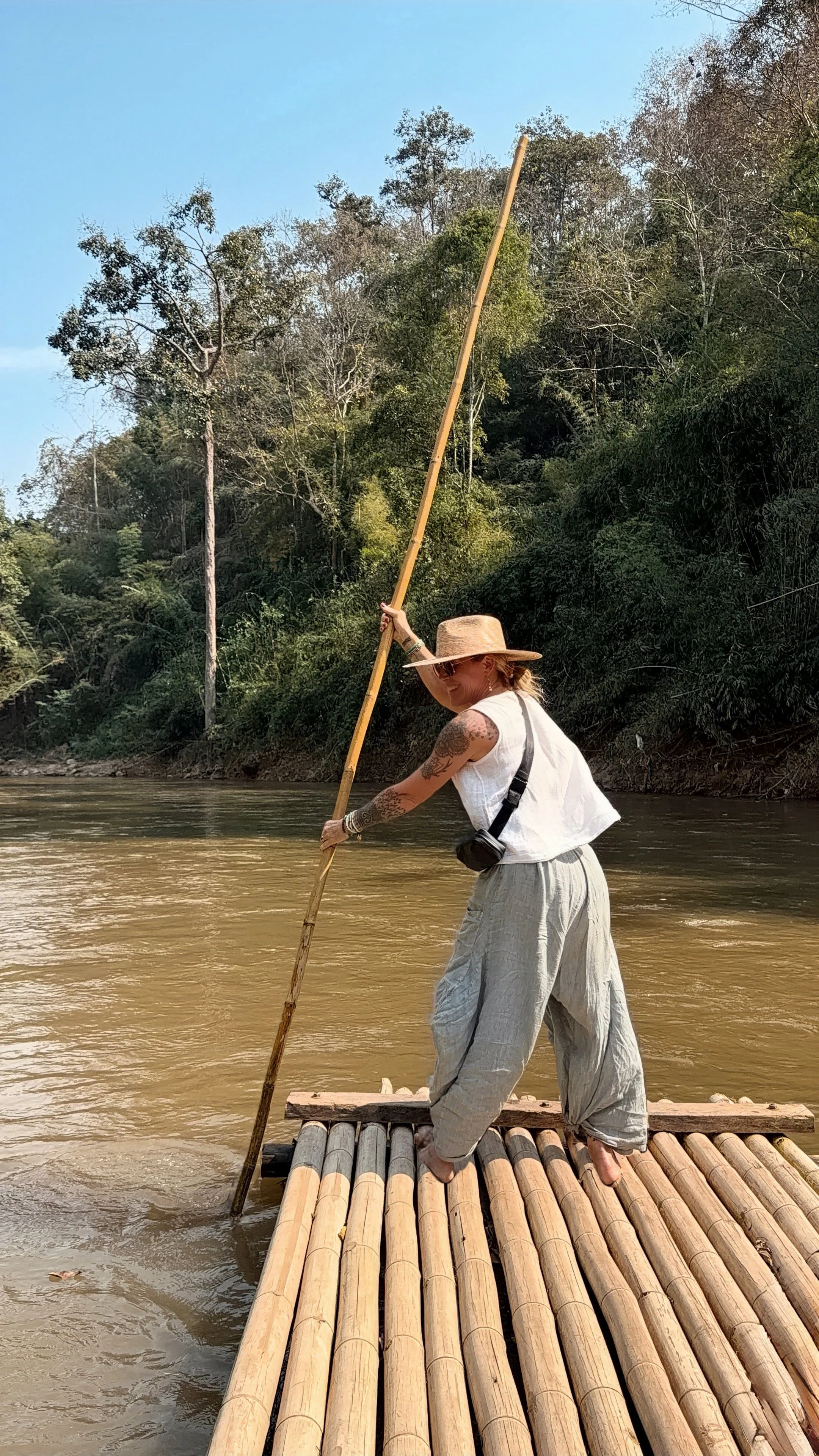 Woman navigating a bamboo raft on a river in Thailand, a metaphor for adaptability and intentional travel with G&G Adventures.