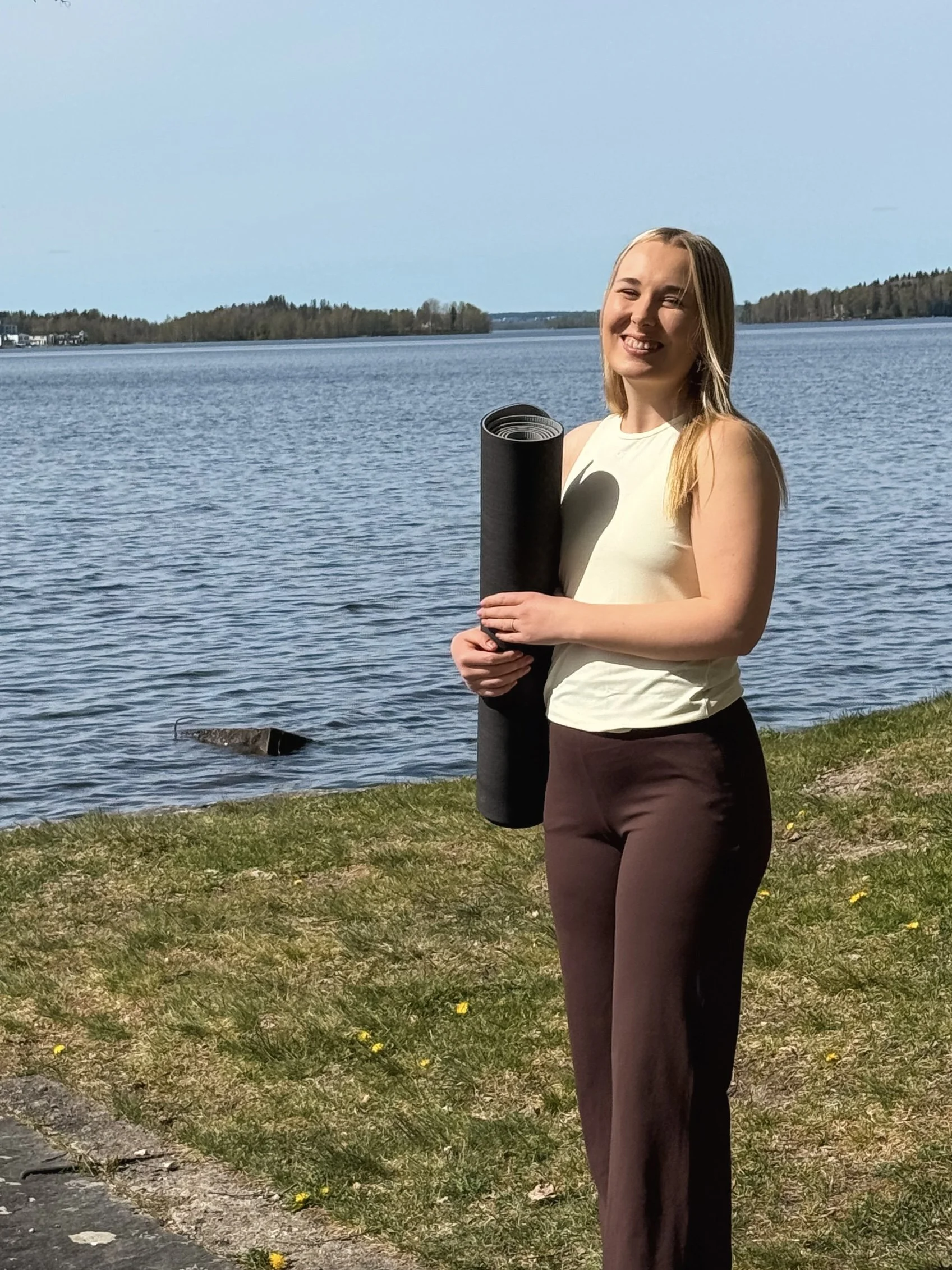 Hibi Eventsin perustaja Tytti Vainio-Mattila hymyilee rannalla joogamantto kainalossa.