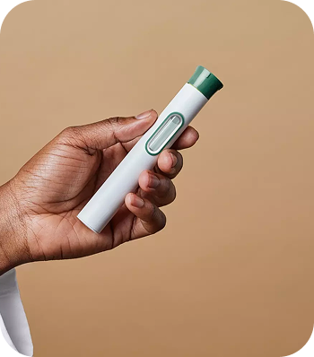A hand holding a small, white and green electronic device against a beige background.