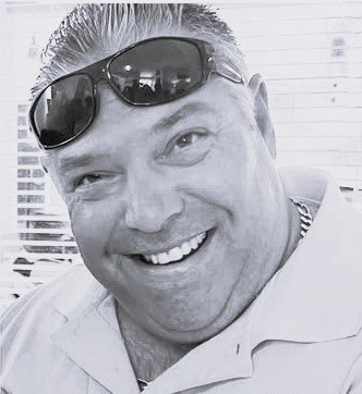 A man smiling with sunglasses on his head in a casual setting. Sean McFarran