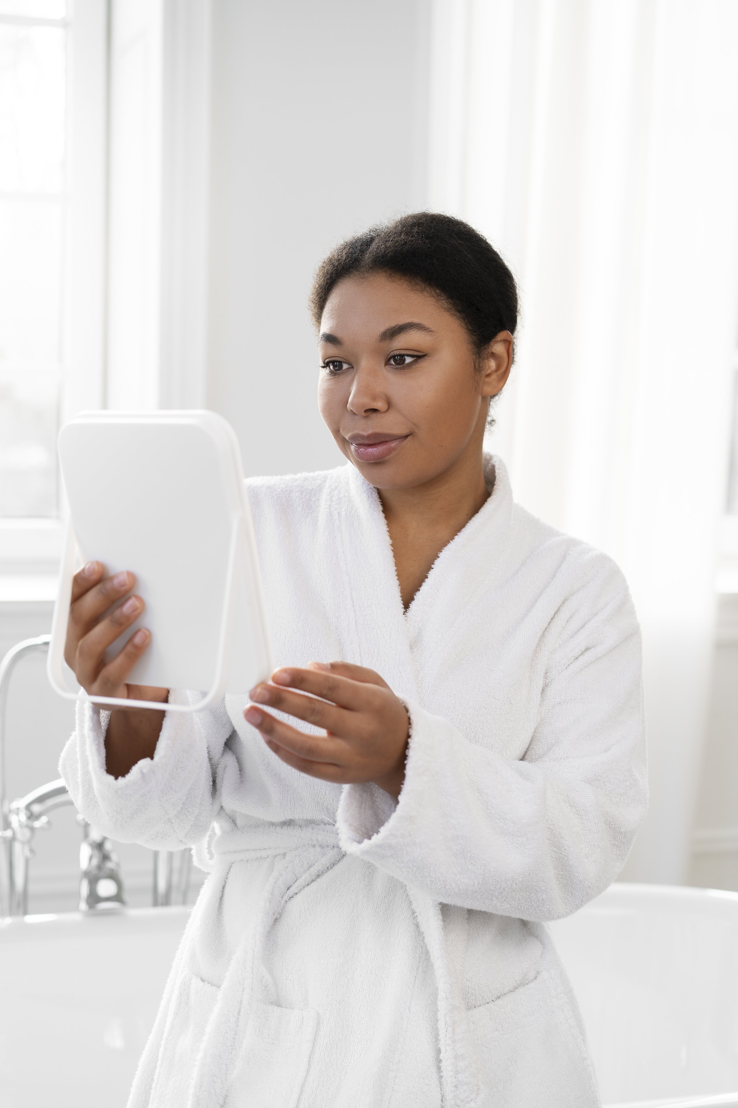 Woman in a white robe looking at a mirror