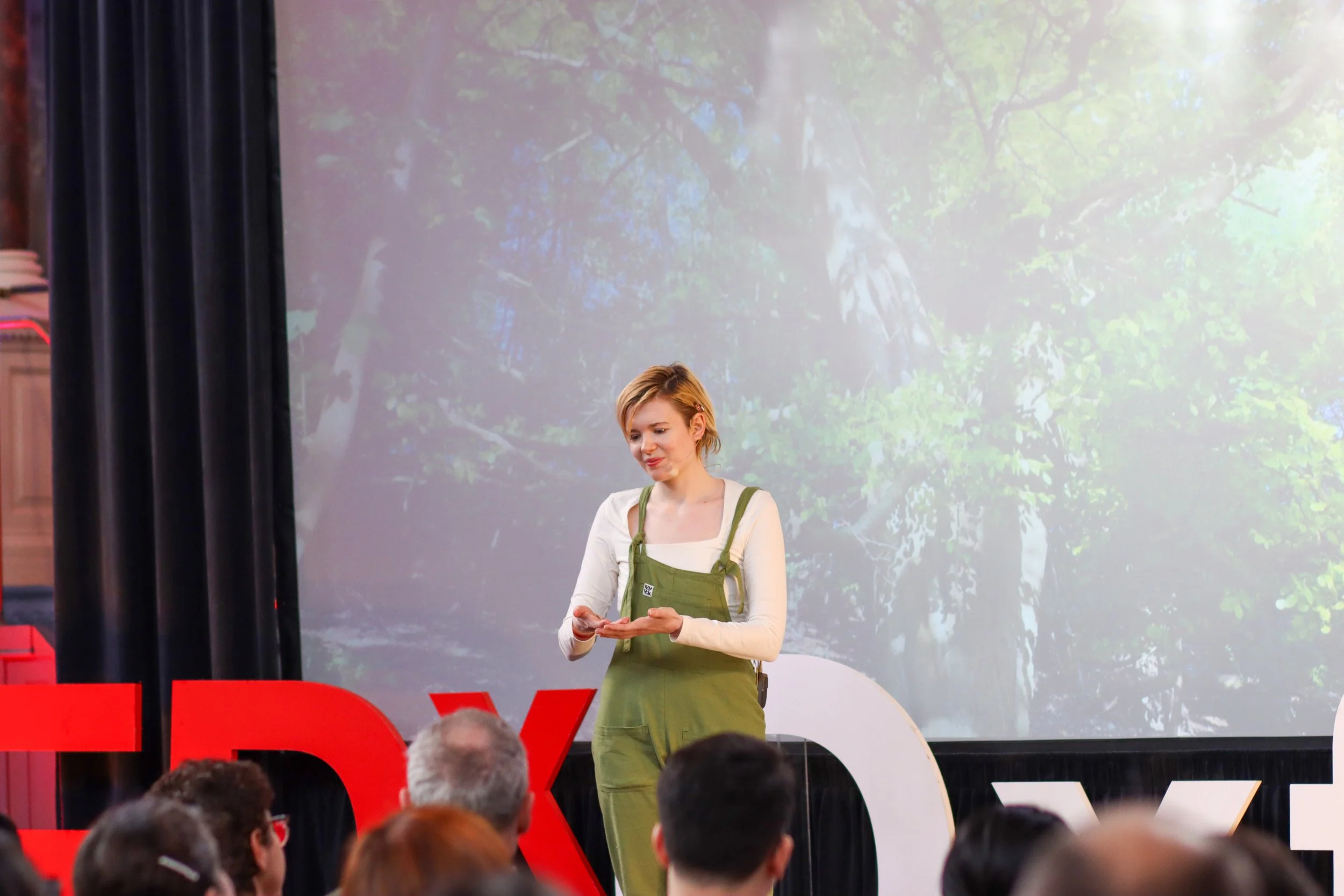 Lucy Grabe-Watson at TEDx Oxford speaking, looking at hand, January 2026 Official Photo