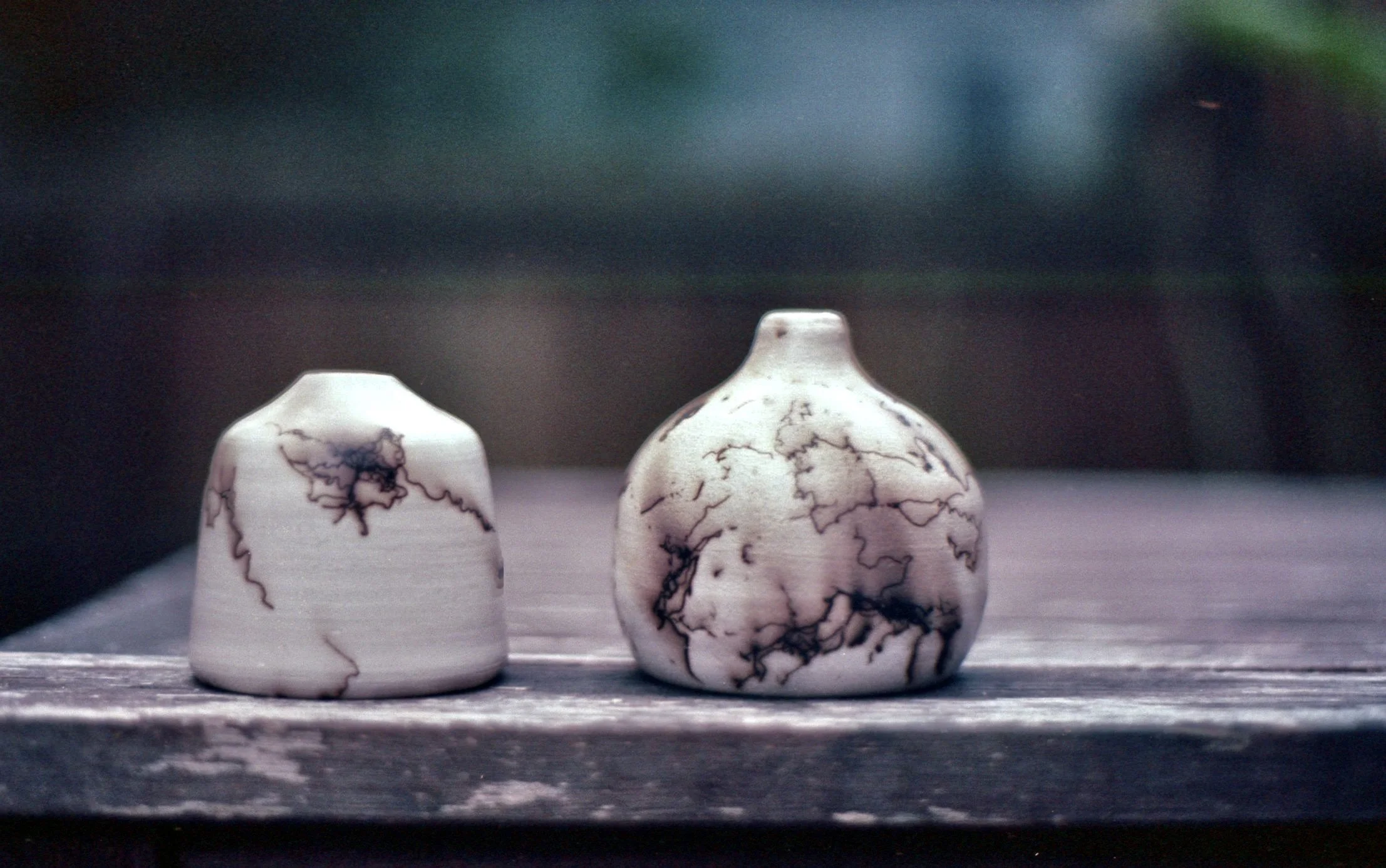 Two small ceramic vases with black marbled patterns placed on a wooden surface.