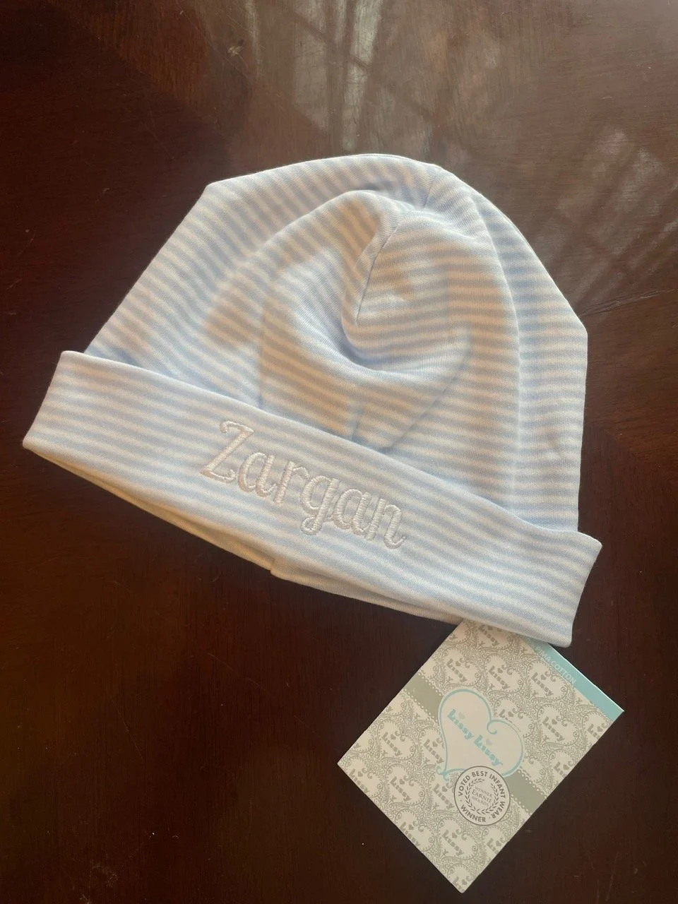 Image shows a blue and white stripped baby hat with the name "Zargan" machine embroidered onto it.