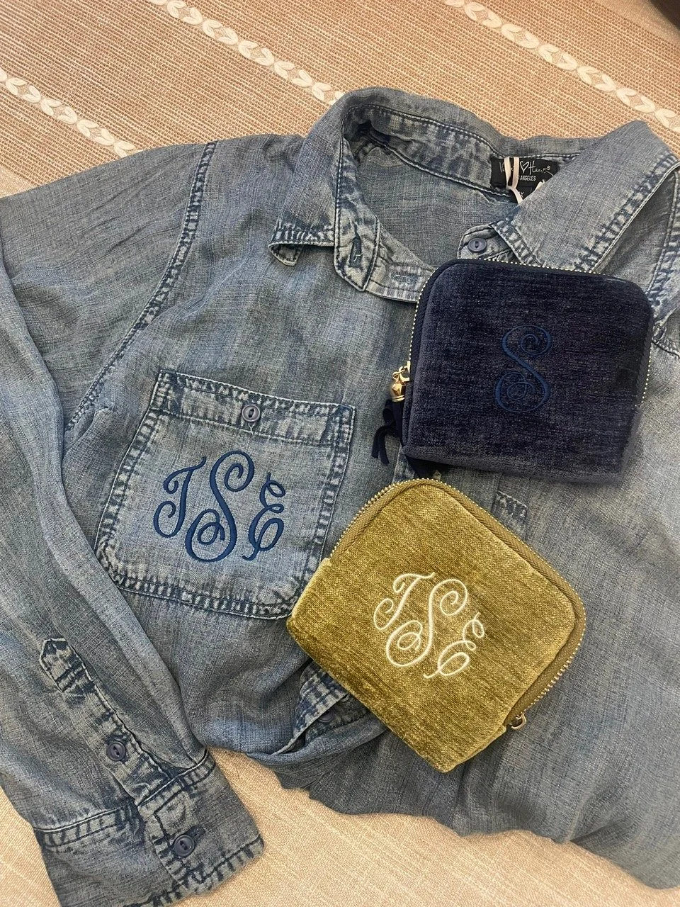 Image shows a denim jacket along with two jewelry pouches that are machine embroidered. The jacket and one pouch have the monogram TSE and the other pouch has an S.