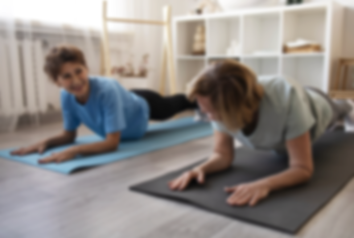 Deux personnes faisant des exercices de yoga sur des tapis dans une pièce lumineuse.