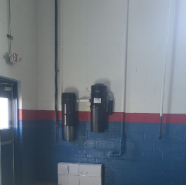 Industrial equipment mounted on a wall in a warehouse or factory setting.