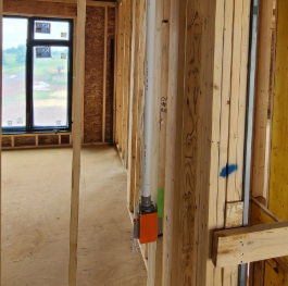 Interior of a construction site showing wooden wall studs, electrical wiring, and an orange electrical box.