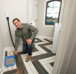 Man kneeling on bathroom floor next to a pet litter box, smiling at camera