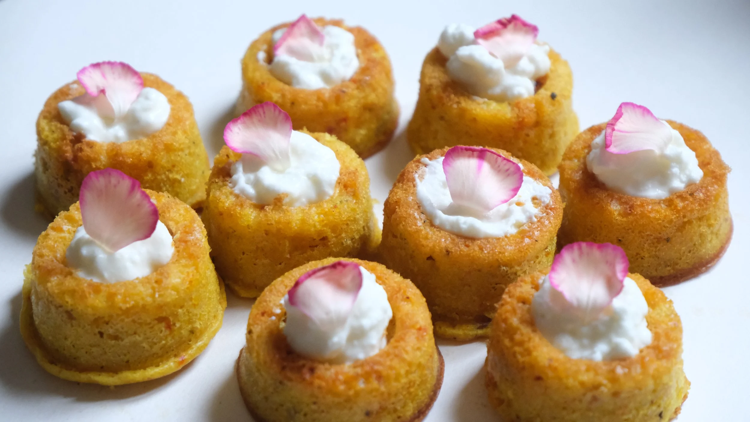 Mini cheesecakes garnis de crème et de pétales de rose