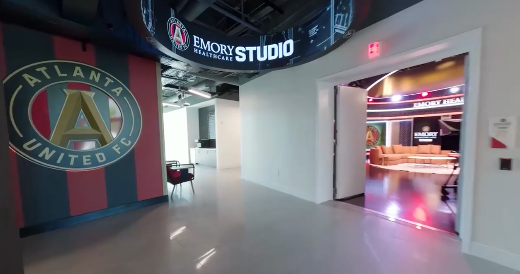 Entrance to Emory Healthcare Studio with Atlanta United FC logo on the wall, and a view into a lounge area with seating and colorful lighting.