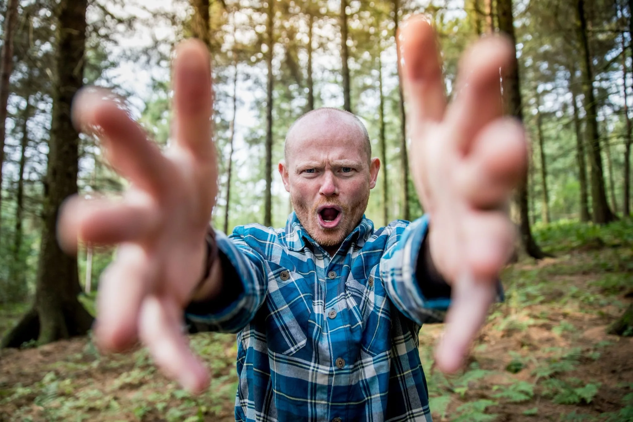 Danny Bent reaching toward the camera in a forest setting