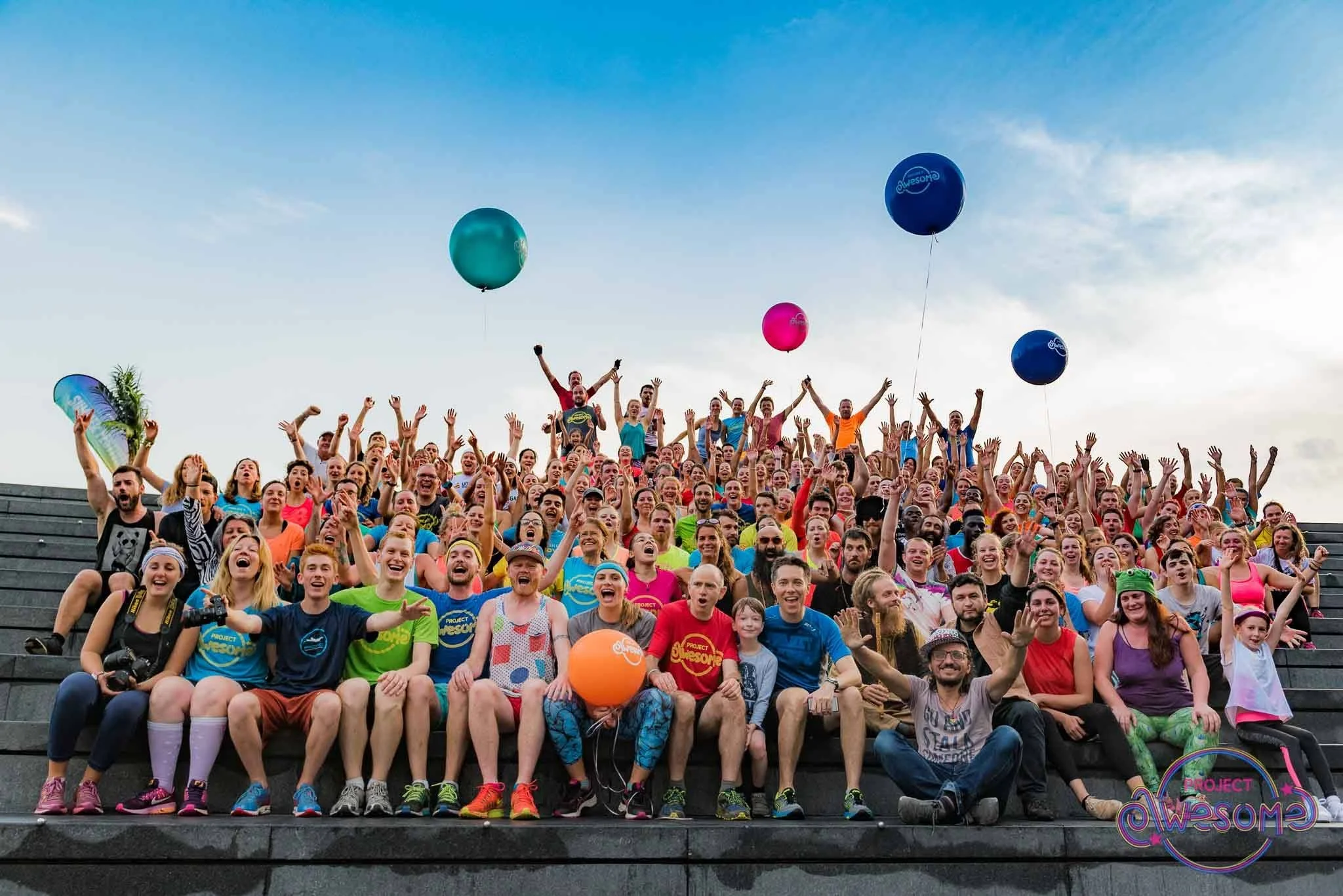 Large crowd from Project Awesome gathered outdoors on steps with balloons