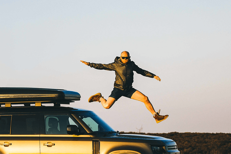 Danny Bent jumping from a vehicle during a nomadic adventure journey