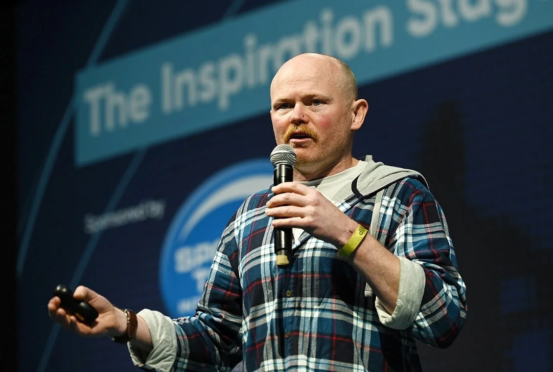 Danny Bent delivering a keynote talk on stage to a live audience