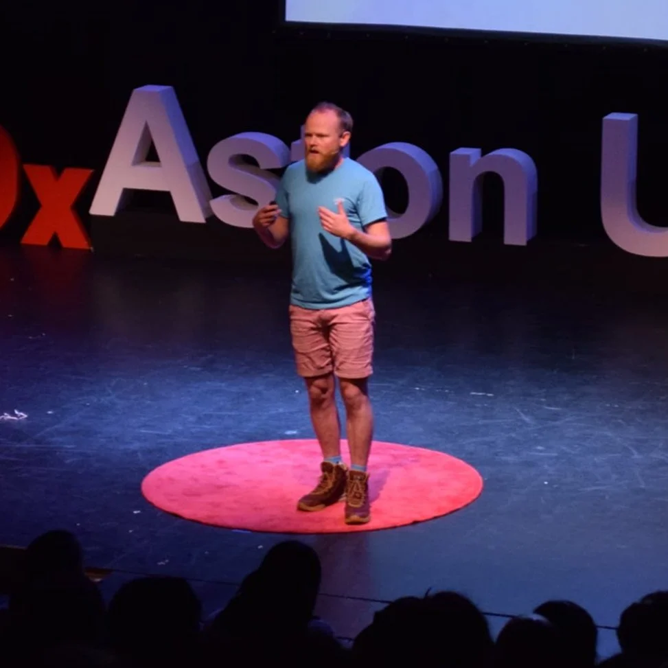 Danny Bent speaking on stage during a TEDx talk